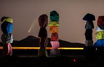 The comet Neowise is visible in the evening sky above the artwork titled: “Seven Magic Mountains” by artist Ugo Rondinone. Near Las Vegas, Nevada, USA. July 16, 2020