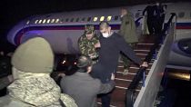 In this photo taken from the Russian Defense Ministry, an Armenian captive is escorted off a Russian military plane upon arrival outside Yerevan, Armenia, Dec. 14, 2020
