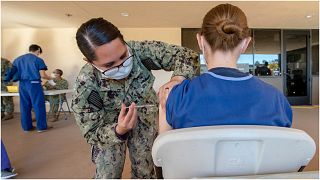 جندية أمريكية تقدم لقاحا لمتطوعة في مركز لعلاج المصابين بكورونا
