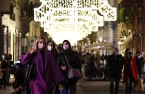 People wearing face masks to curb the spread of COVID-19 stroll along a shopping street decorated for Christmas, in downtown Rome, Monday, Dec. 14, 2020
