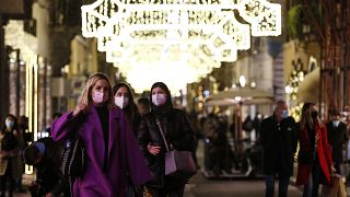 People wearing face masks to curb the spread of COVID-19 stroll along a shopping street decorated for Christmas, in downtown Rome, Monday, Dec. 14, 2020