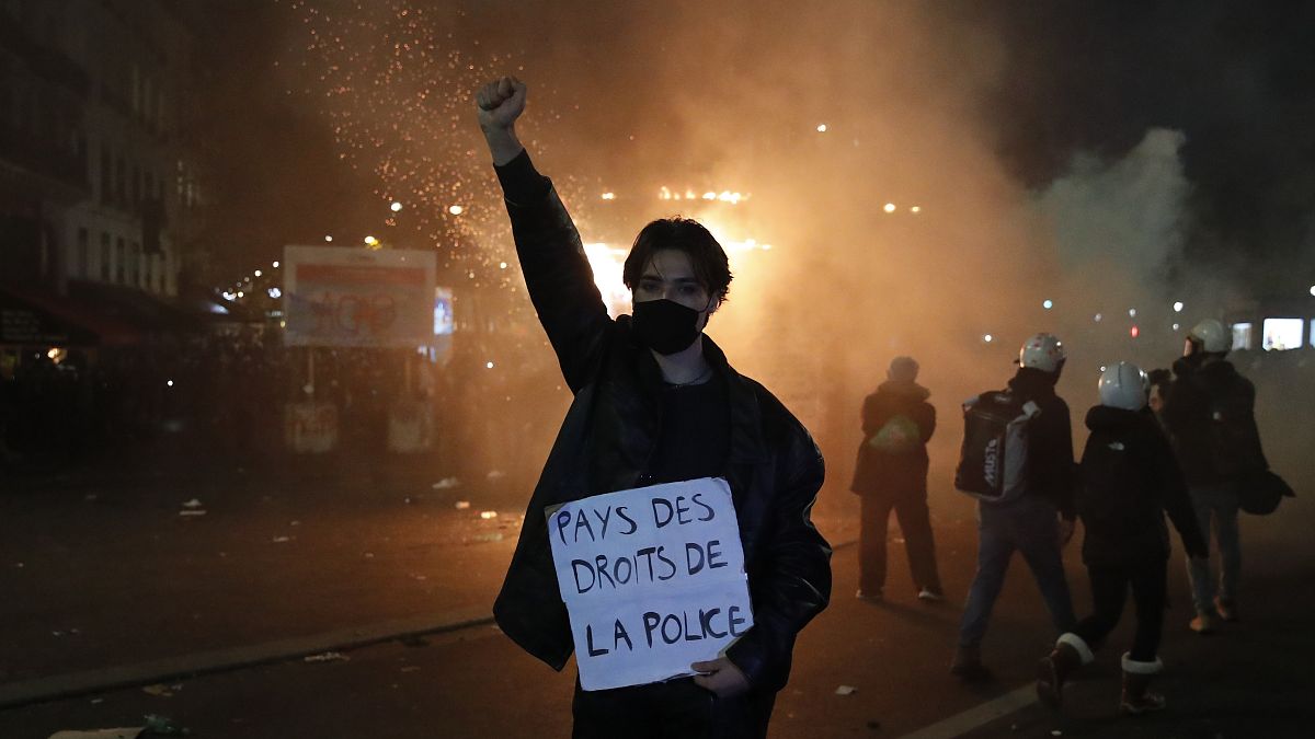 متظاهر يحمل لافتة كتب عليها "أرض حقوق الإنسان  الشرطة" خلال مظاهرة ضد قانون الأمن في فرنسا. 