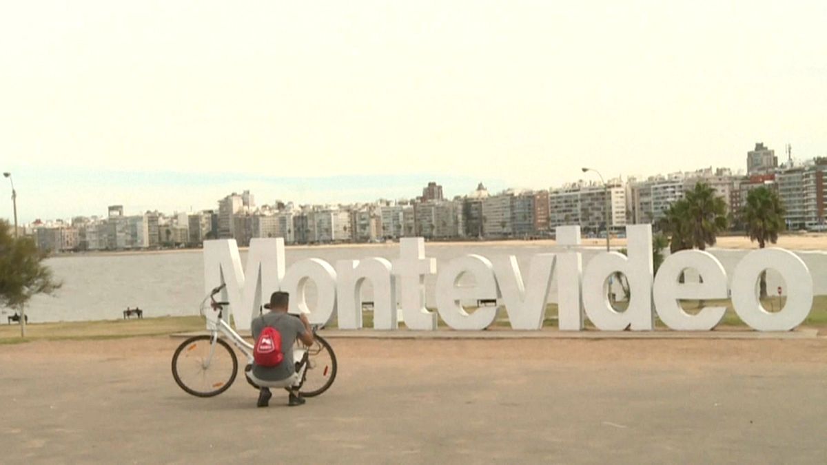 Un ciclista arregla su bicicleta con Montevideo al fondo, Montevideo, Uruguay