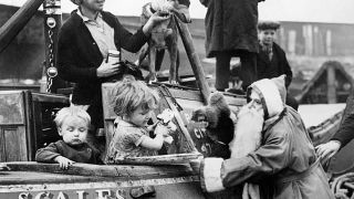 21 dicembre 1938: un uomo vestito da Babbo Natale distribuisce giocattoli ai bambini che secondono da una chiatta nel porto di Brentford, Regno Unito