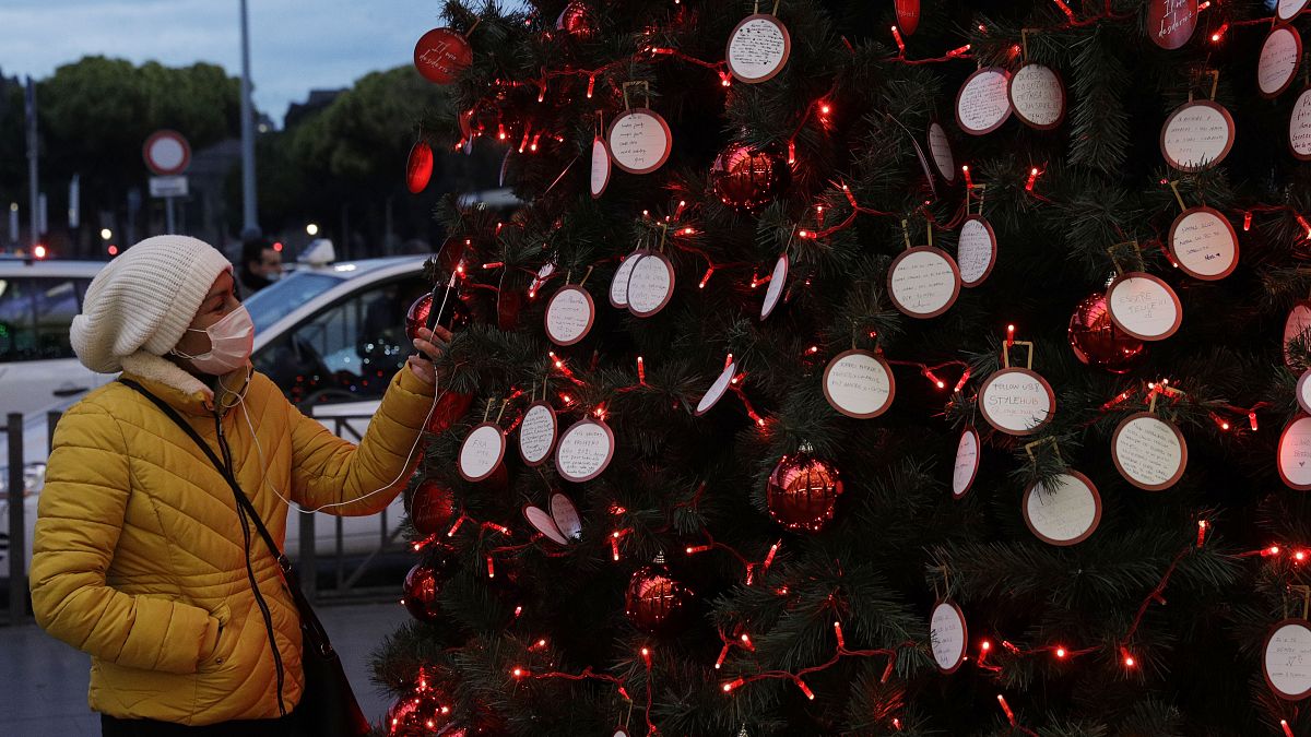 A woman takes a picture at messages adorning a Christmas tree outside Rome's Termini railway station,  Dec.10, 2020.
