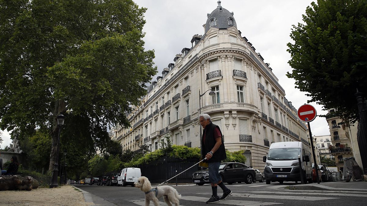 FILE - A man walks his dog next to an apartment building owned by Jeffrey Epstein in the 16th district in Paris, Tuesday, Aug. 13, 2019.