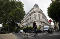 FILE - A man walks his dog next to an apartment building owned by Jeffrey Epstein in the 16th district in Paris, Tuesday, Aug. 13, 2019.