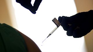 A droplet falls from a syringe after a health care worker is injected with the Pfizer-BioNTech COVID-19 vaccine