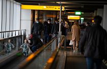 In this Friday Dec. 18, 2020, file photo, arriving and departing passengers use the flat escalators at Schiphol Airport, near Amsterdam, Netherlands.