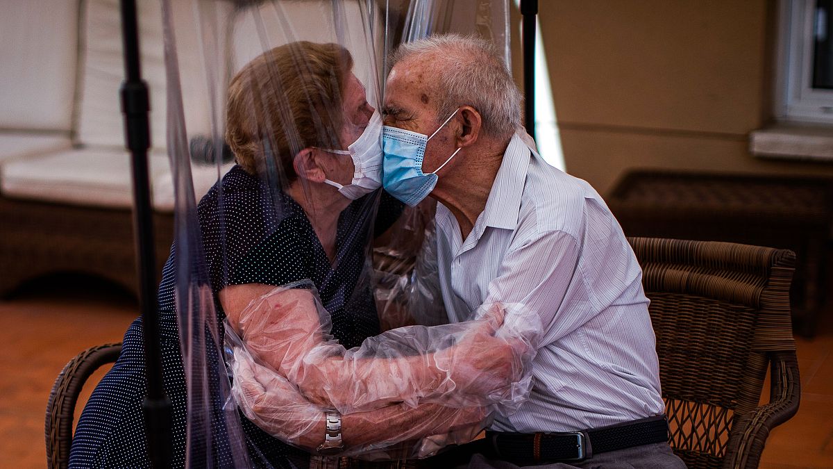 Agustina Cañamero e Pascual Pérez si baciano attraverso un telo di plastica per evitare il contagio da coronavirus in una residenza per anziani di Barcellona