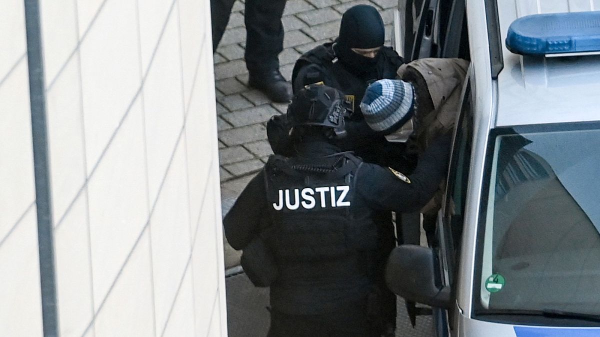 The defendant Stephan Balliet is escorted from the vehicle by court personnel upon his arrival at the district court in Magdeburg, Germany, Monday, Dec. 21, 2020.