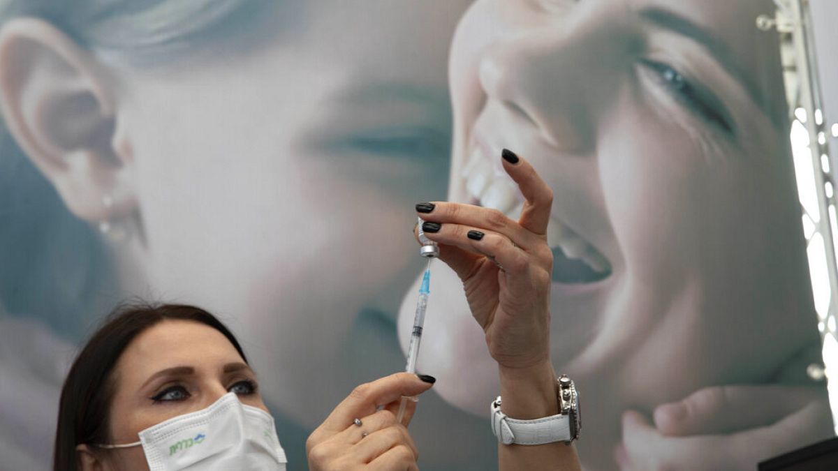 An Israeli nurse prepares a COVID-19 vaccine at a temporary vaccination center in the lobby of a gymnasium in Tel Aviv