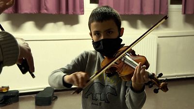 Child playing violin with teacher