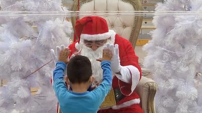 Boy placing hands up to Santa's hands on bubble
