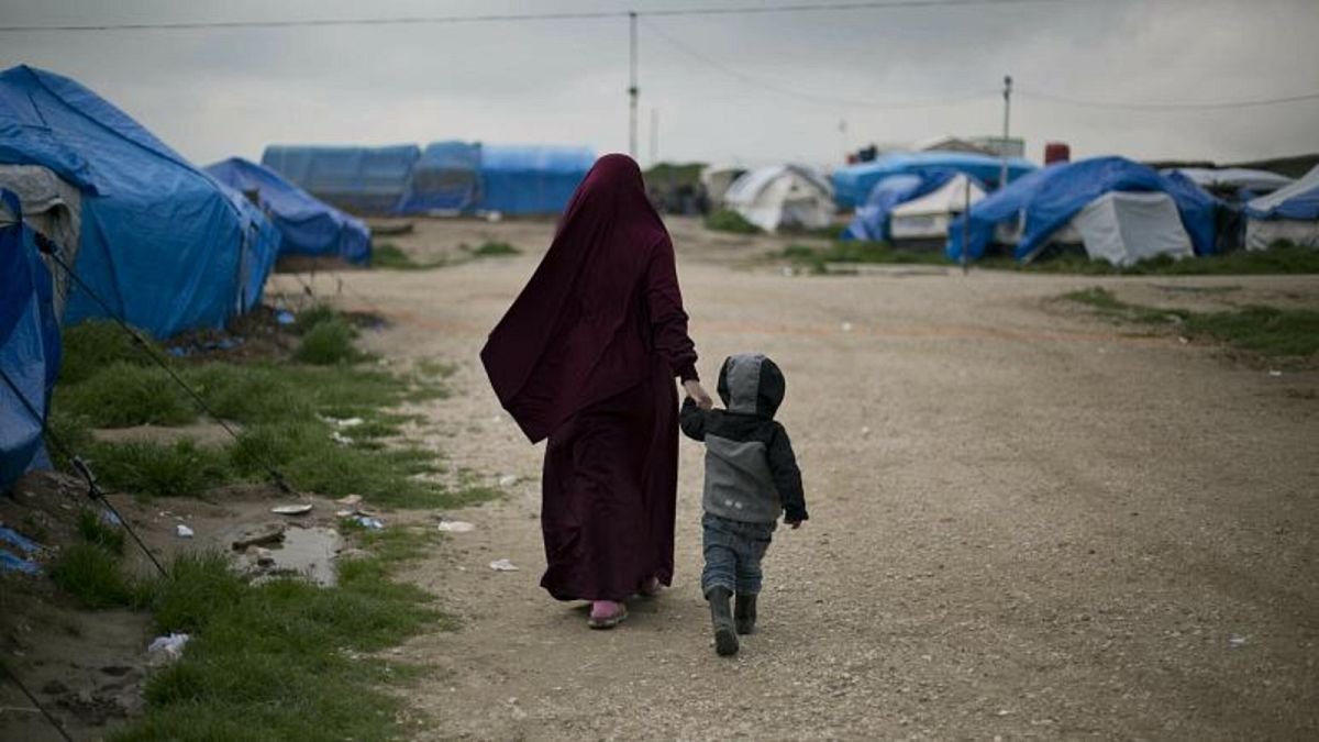 أمرأة تسير مع طفلها داخل معسكر الهول شمال شرق سوريا حيث تحتجز القوات الكردية الآلاف من نساء وأطفال عناصر في تنظيم الدولة الإسلامية