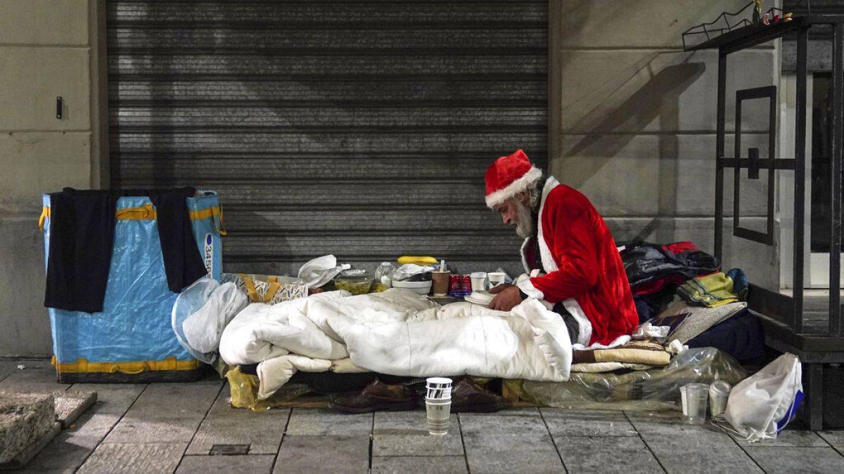 A homeless man, name given Rafael, wears a Santa Claus outfit as he prepares to have dinner by the side of a road, in Milan, Italy