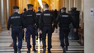 FILE: French gendarmes walk in the corridor of the hall of justice, Thursday, Dec. 17, 2020 in Paris.