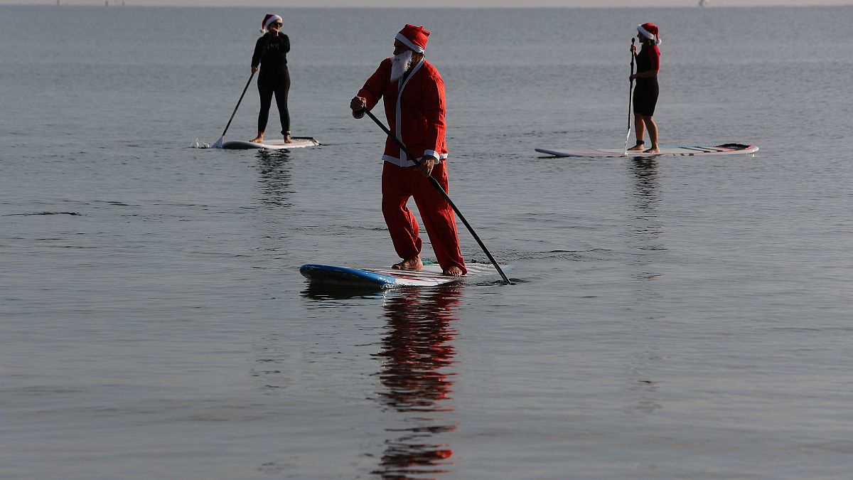 Members of a windsurfing center wear Santa Claus costumes as they paddle on stand up boards during Christmas celebrations in southern costal city of Larnaca, Cyprus