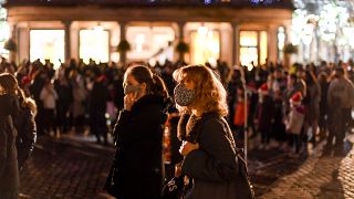 People wear face masks as they walk in Covent Garden, in London, Saturday, Dec. 12, 2020.