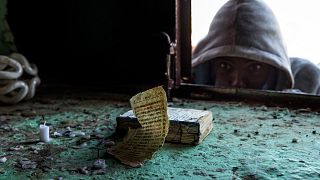 A boy who fled the conflict in Ethiopia's Tigray region looks at an Ethiopian priest's Bible near Umm Rakouba refugee camp in Qadarif, eastern Sudan.