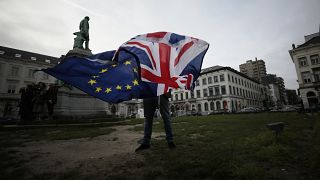 رجل يرفع علمي الاتحاد وبريطانيا في بروكسل