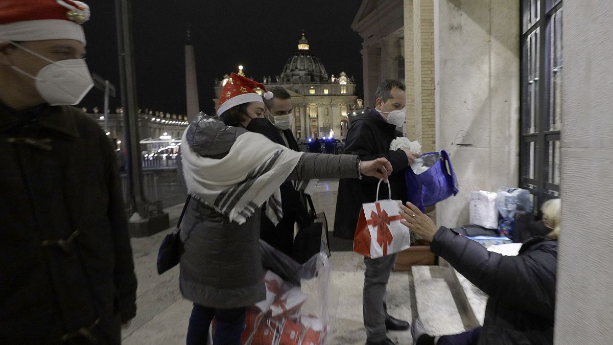 Voluntarios de la Comunidad de San Egidio distribuyen alimentos y regalos a las personas sin hogar fuera de la Plaza de San Pedro en el Vaticano, el 24 de diciembre de 2020.