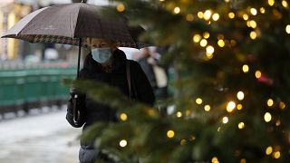 A pedestrian passes Christmas decorations of a closed shop in Oxford Street in London