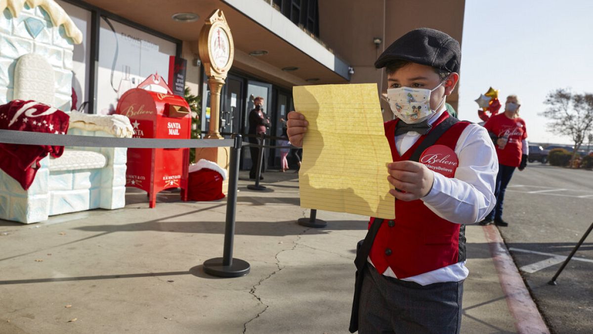 طفل يقرأ رسالة الأمنيات إلى سانتا كلوس قبل أن يضعها في صندوق البريد