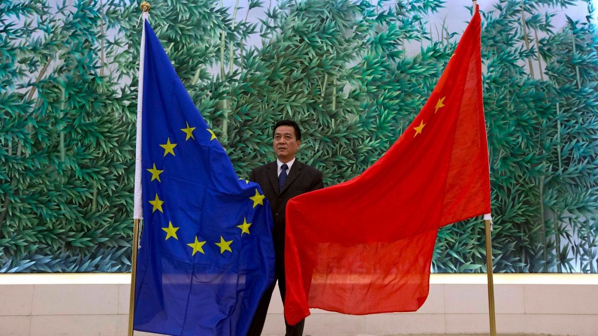 مقام چینی در کنار پرچم کشورش و اتحادیه اروپا در جریان مذاکرات سال ۲۰۱۳