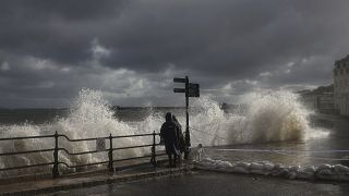 FILE PHOTO - People watch as waves crash along the coast at Swanage in Dorset, England, Friday, Oct. 2, 2020. 