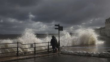 FILE PHOTO - People watch as waves crash along the coast at Swanage in Dorset, England, Friday, Oct. 2, 2020. 