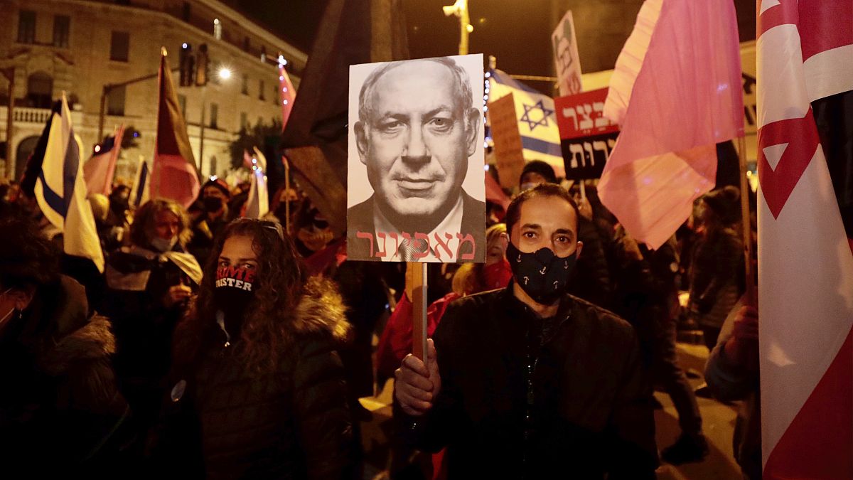 Un homme tient un portrait de Benjamin Netanyahou légendé "membre de la mafia" lors d'une manifestation réclamant sa démission, le 26 décembre 2020, à Jérusalem