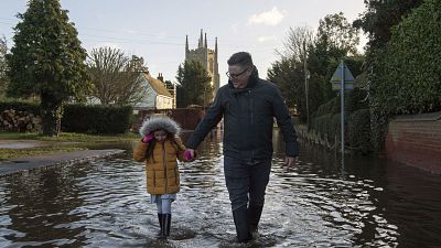 A man and girl walk through the flood water, in Great Barford, in Bedfordshire, England.