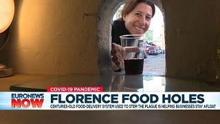 A woman picks up a glass of wine through a 'buchetta' (little hole) in Florence