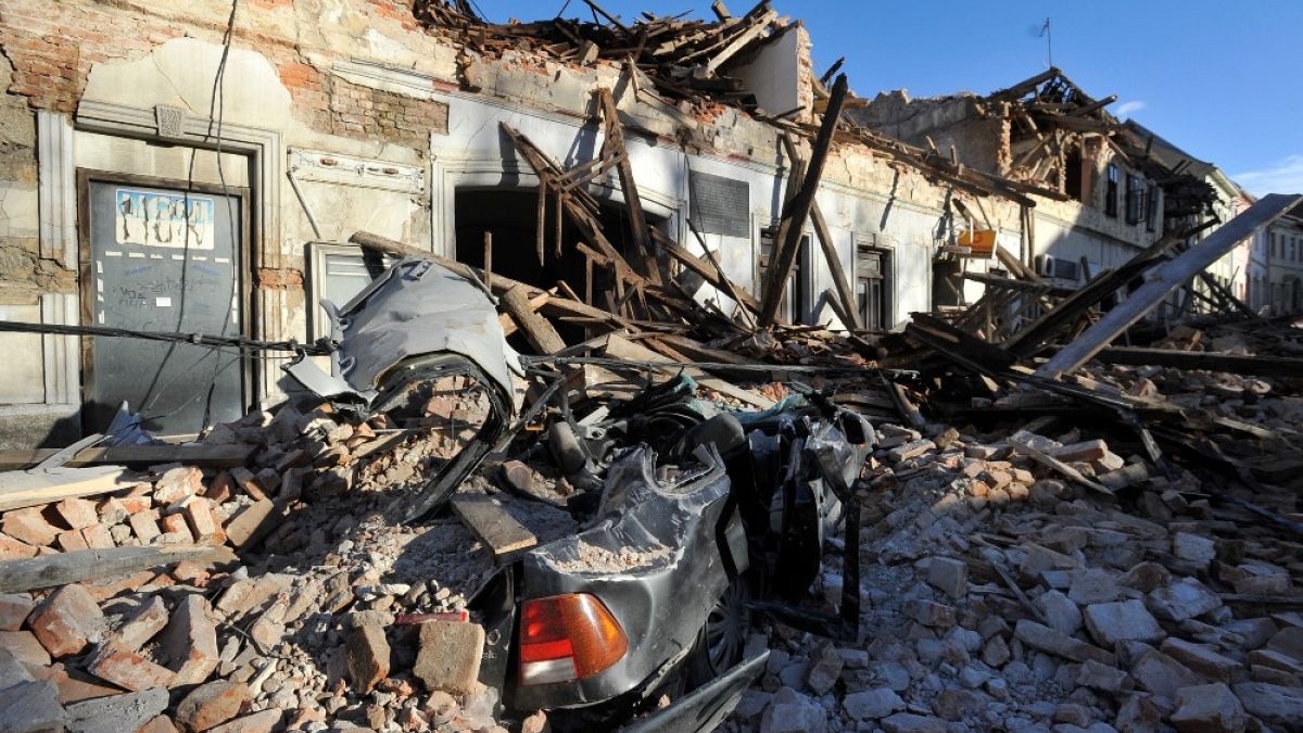 Resti di un'auto coperta da detriti e di edifici danneggiati dal terremoto a Petrinja, Croazia