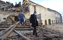 People move through remains of a building damaged in an earthquake, in Petrinja, Croatia, Tuesday, Dec. 29, 2020. 