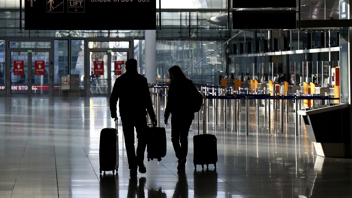 People walk through a deserted check-in hall at the airport in Munich, Germany, Saturday, December 26, 2020.