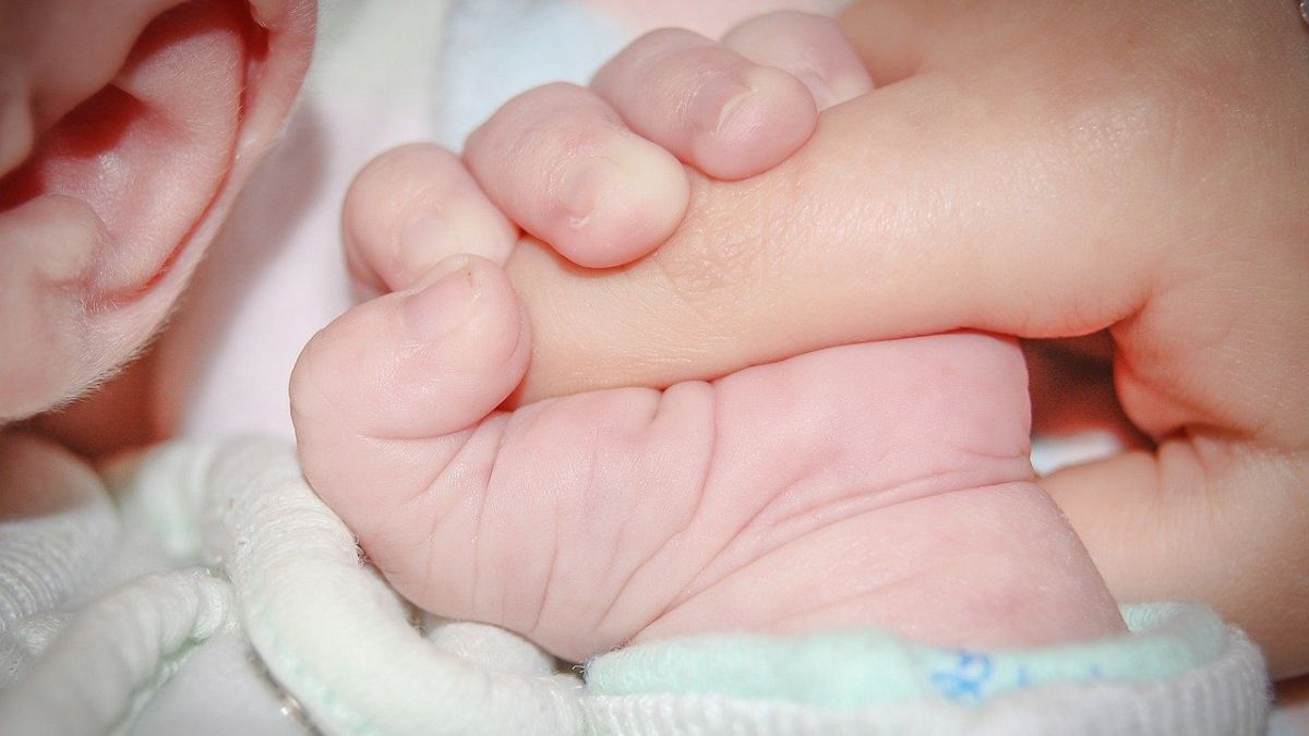 Baby umklammert Finger eines Erwachsenen