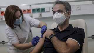 Greece's Prime Minister Kyriakos Mitsotakis, right, receives an injection with a dose of COVID-19 vaccine, at the Attikon University Hospital in Athens, Dec. 27, 2020.