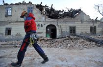 A rescuer walks past a building damaged in Petrinja.