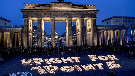 Activists light candles in front of the Brandenburg Gate during a protest marking the fifth anniversary of the Paris Agreement signing.