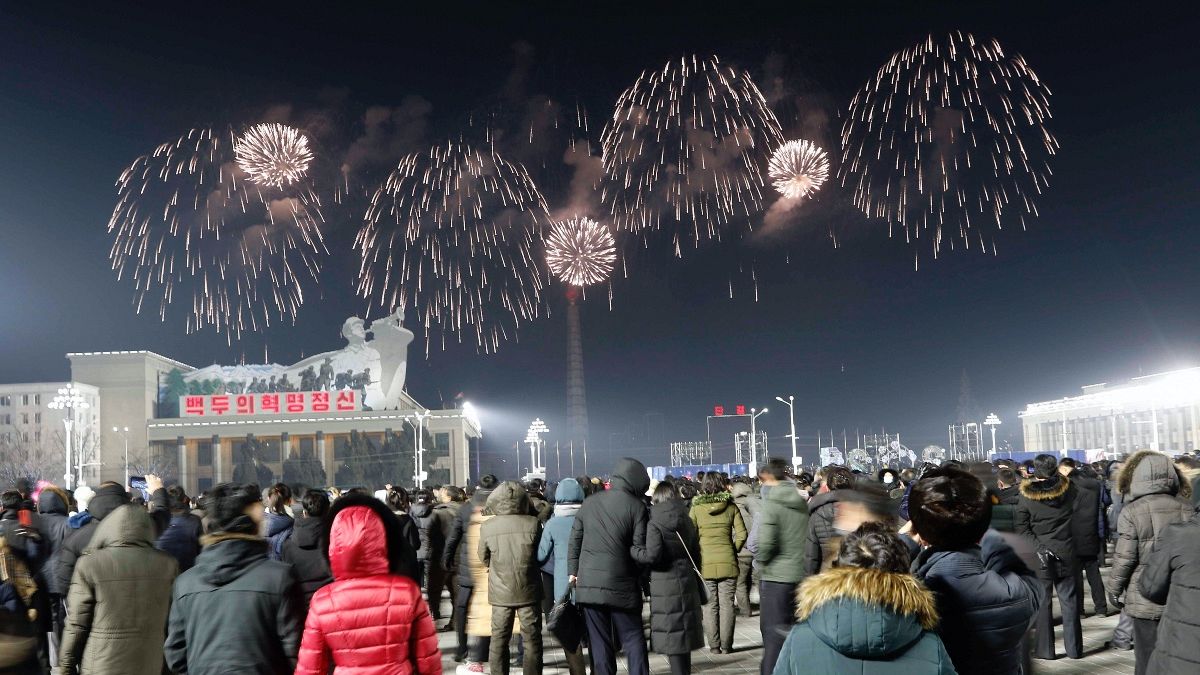 A fireworks display decorates the night sky to celebrate the New Year, as crowds of people look on, at Kim Il Sung Square in Pyongyang, early Friday, Jan., 1, 2021