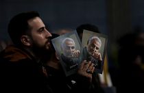 A Hezbollah supporter holds pictures of slain Iranian Revolutionary Guard Gen. Qassem Soleimani.