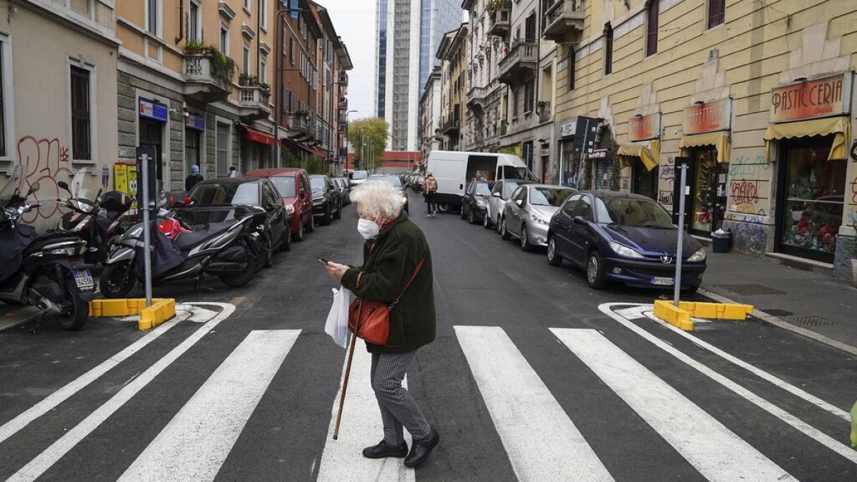 İtalya'da Covid-19 kısıtlamaları altında maske takarak dışarı çıkan yaşlı bir kadın.