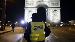 A police officer stand on the Champs Elysees avenue next to the Arc of Triomphe during the New Year's Eve, in Paris, Thursday, Dec. 31, 2020.