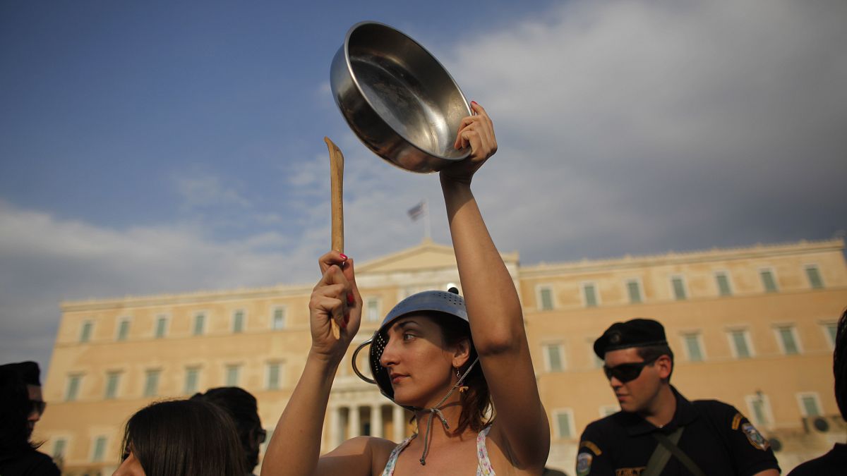 Yunanistan parlamentosu önünde tencere ve tavalara vurarak ses çıkarıp eylem yapan bir grup vatandaş.