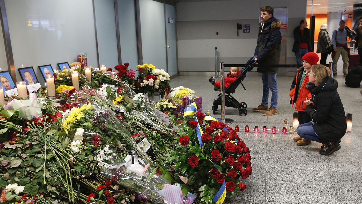 Flowers and candles are placed in front of portraits of the flight crew members of a Ukrainian jet that crashed near Tehran, at the Borispil airport, Ukraine, Jan. 11, 2020.