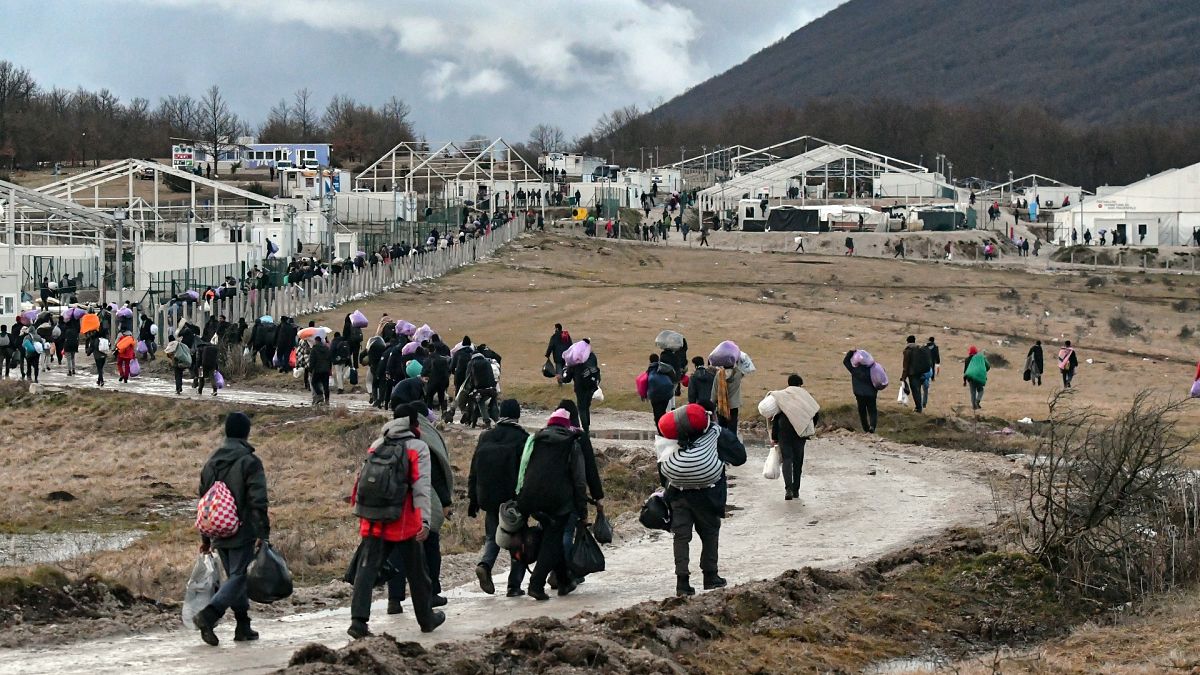 Migrants walk back to the Lipa camp outside Bihac, Bosnia, Wednesday, Dec. 30, 2020, after hundreds failed to be relocated from the burnt-out tent camp.