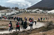 Migrants walk back to the Lipa camp outside Bihac, Bosnia, Wednesday, Dec. 30, 2020, after hundreds failed to be relocated from the burnt-out tent camp.