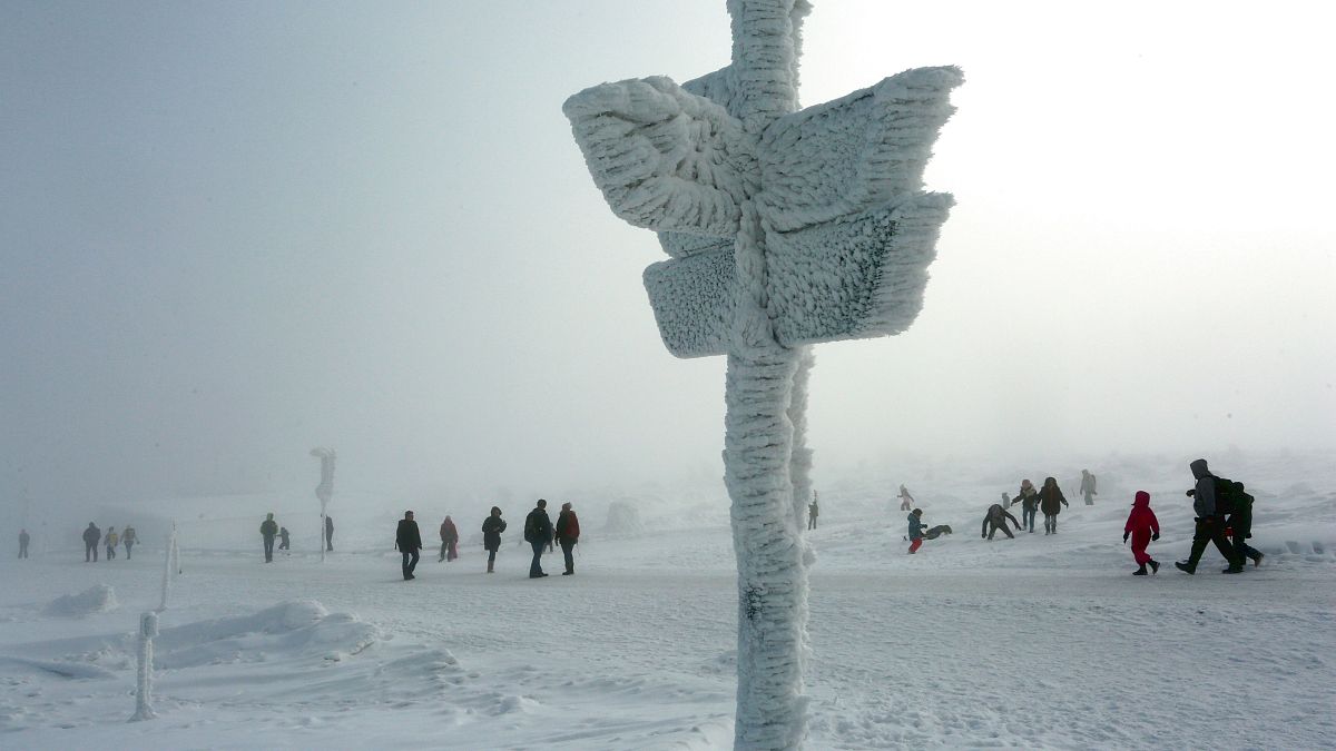 Personas juegas con la nieve junto a una señal helada en Schierke, Alemania